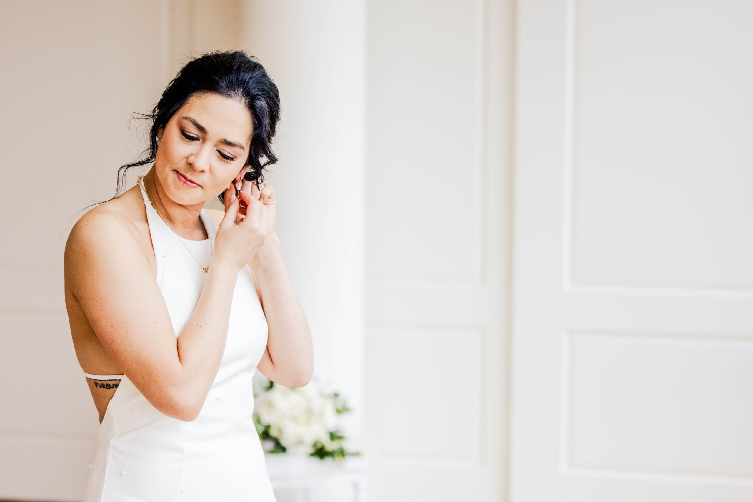 Natural light portrait of the bride putting on her earrings.
