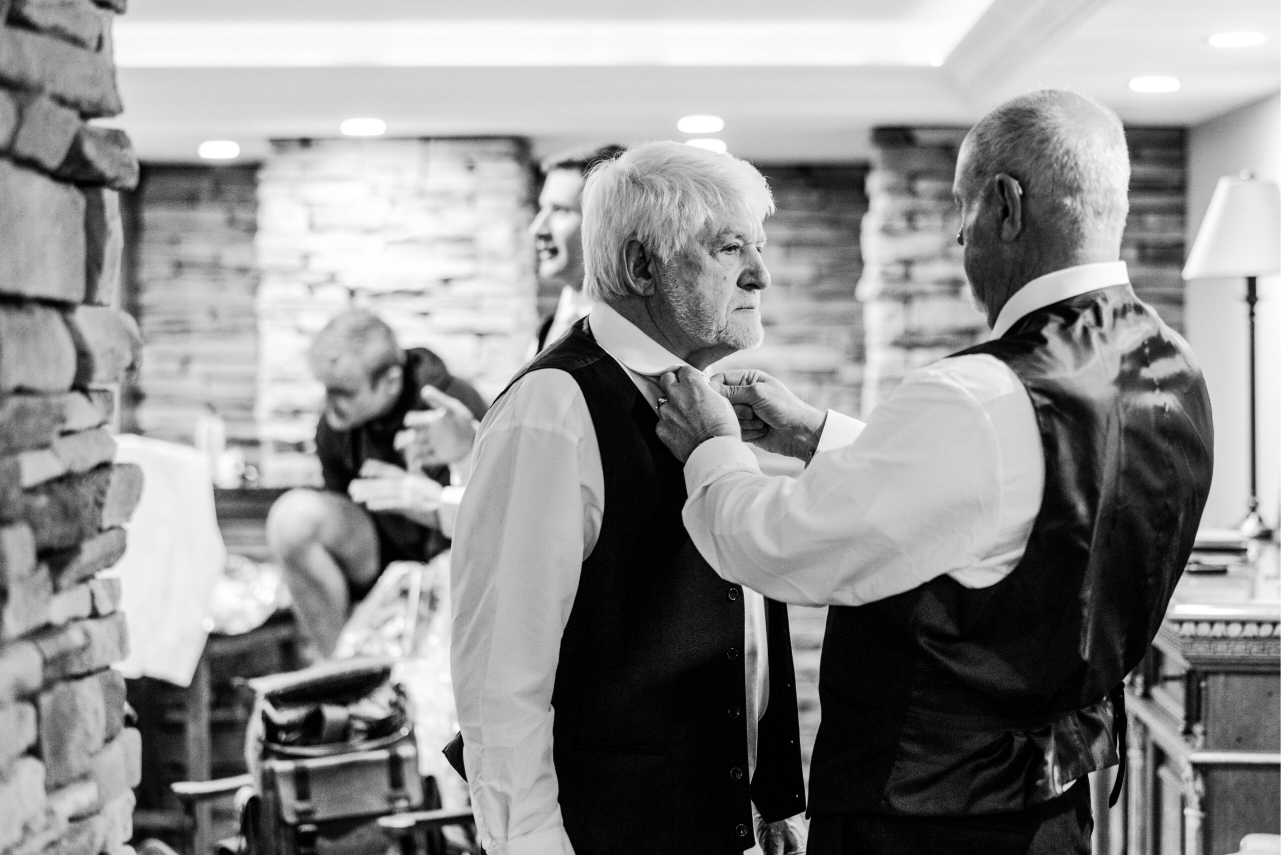 Father helping stepfather of the bride put on a tie