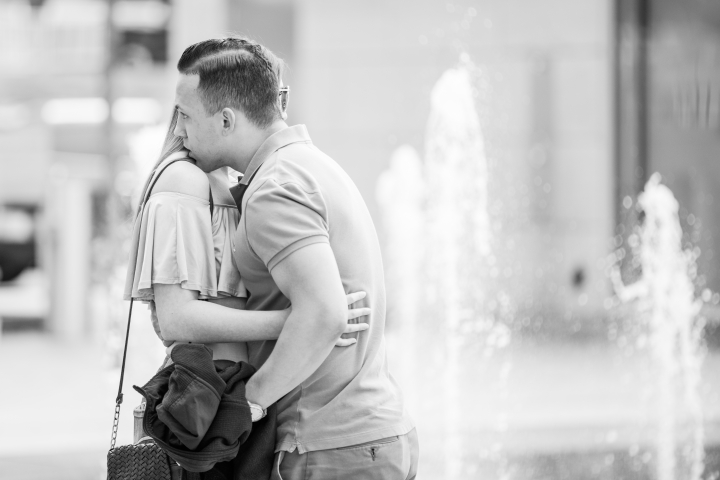 young couple hugging in front of water fountain in downtown cincinnati