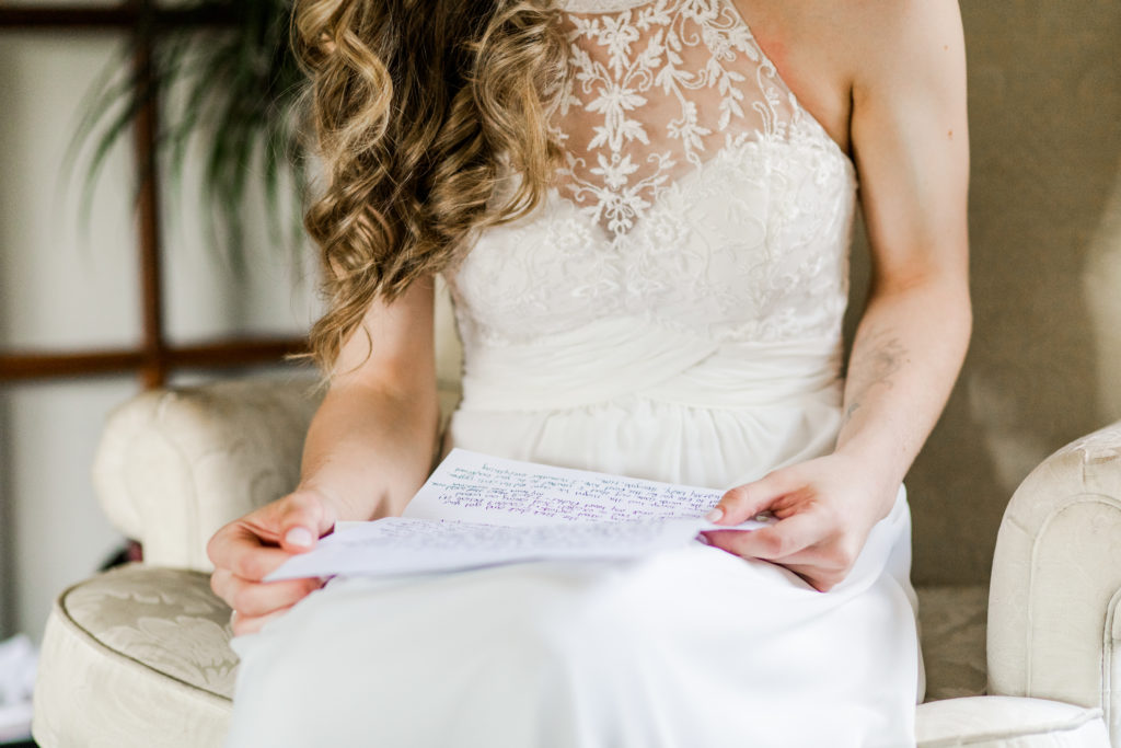 Photo of a bride reading a letter that she received from her future spouse on their wedding day