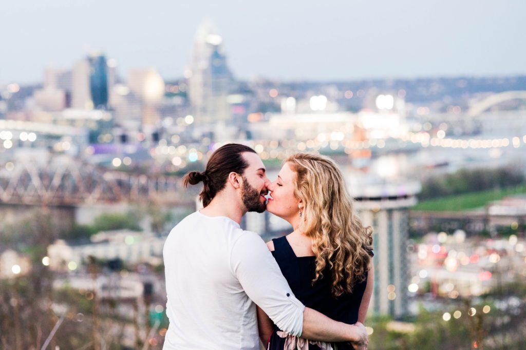 Stacy and Joseph kissing in front of a cityscape during their spring engagement session