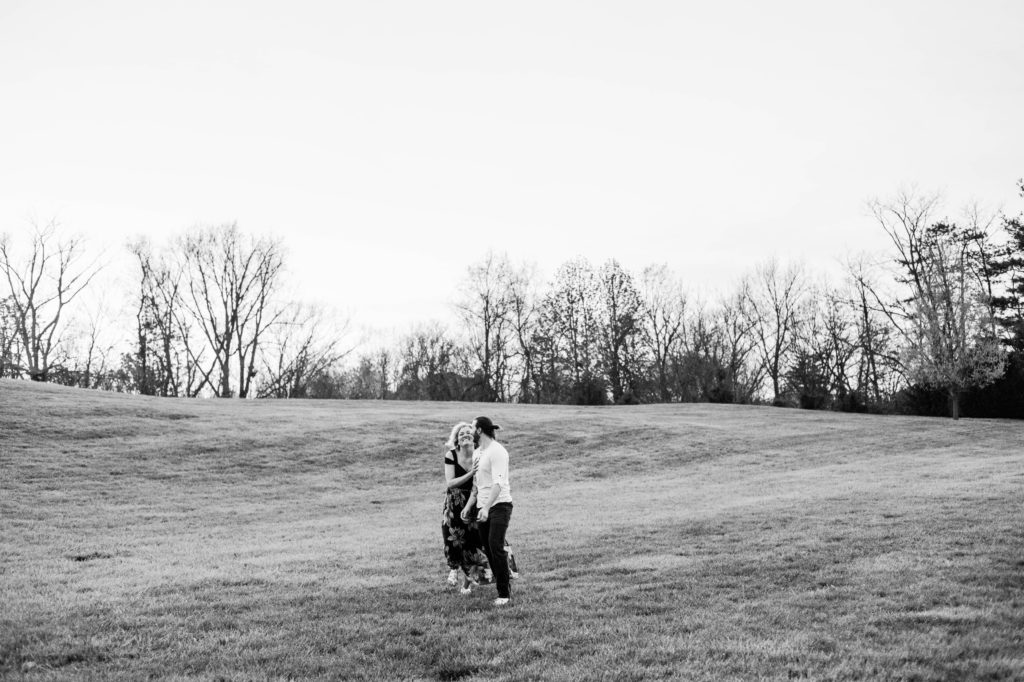 Black and white picture of the couple running through the field together and laughing