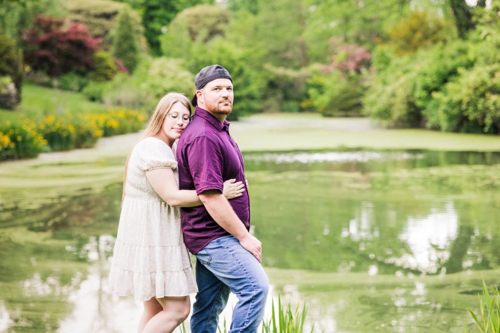 Jasmine gives Brandon a hug from behind as they stand in front of the pond at Mt. Airy Forest