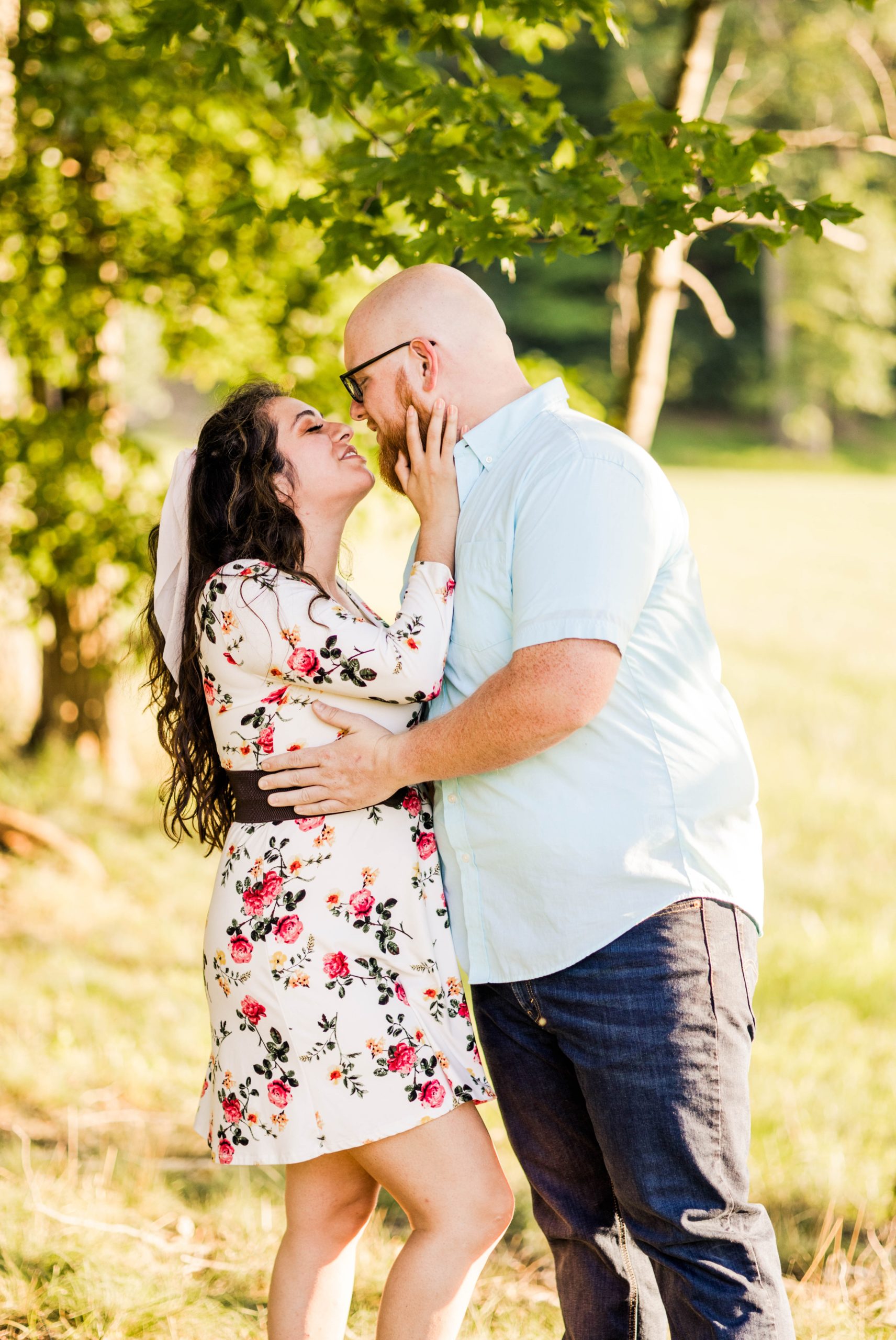 A couple just about to kiss as he rest his hands on her waist and she grabs onto his face during their summer engagement session in Cincinnati Ohio.