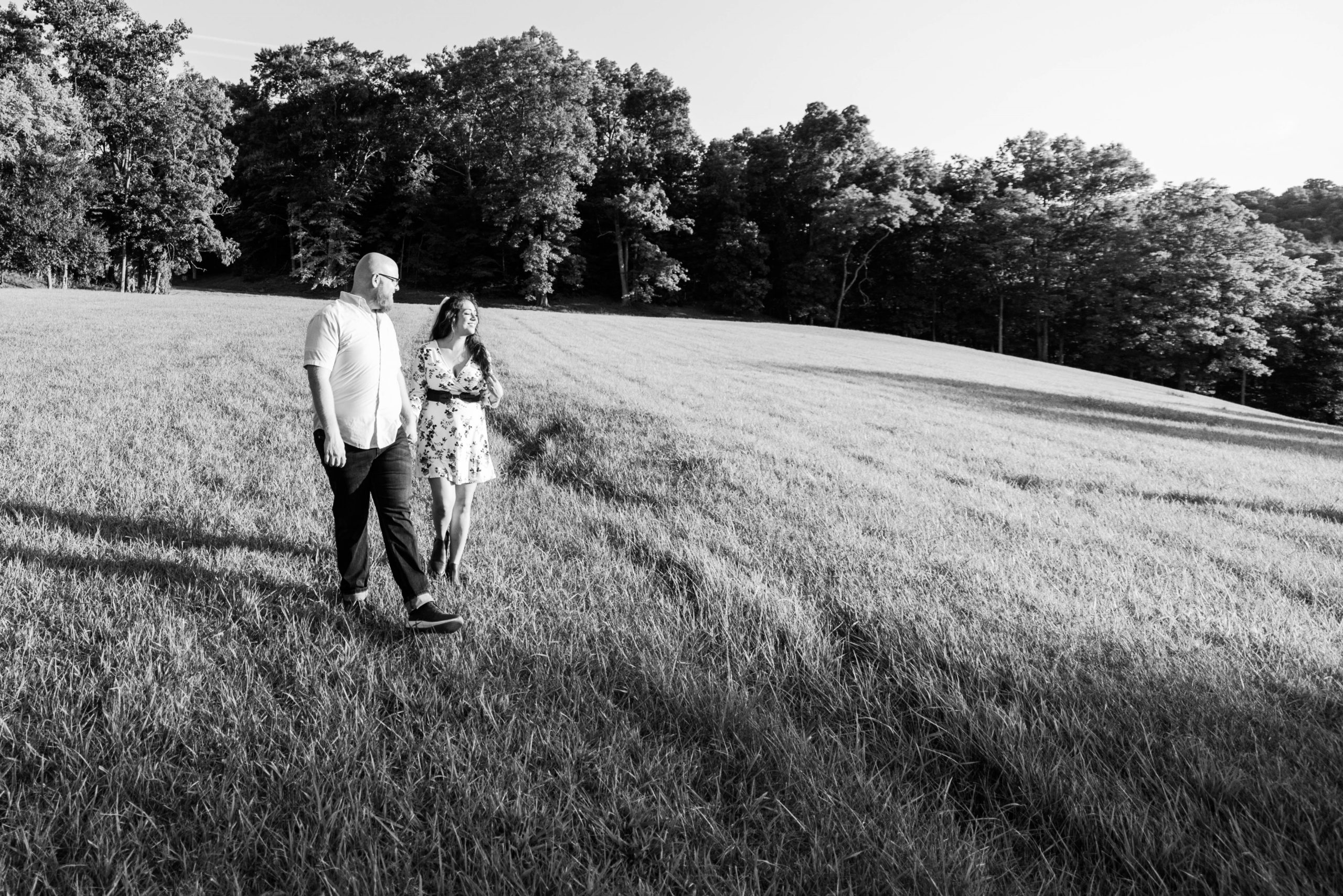Black and white photos of an engaged couple in an open field at East Fork State Park at sunset looking off in the distance smiling during their summer engagement session