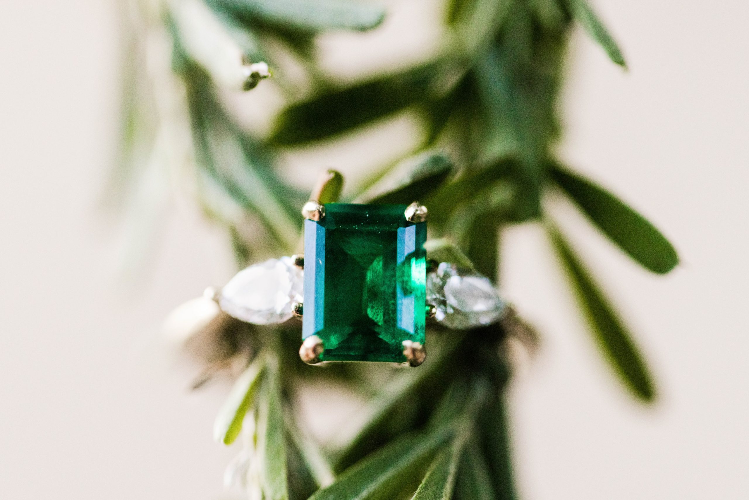 Emerald engagement ring on green leaves 