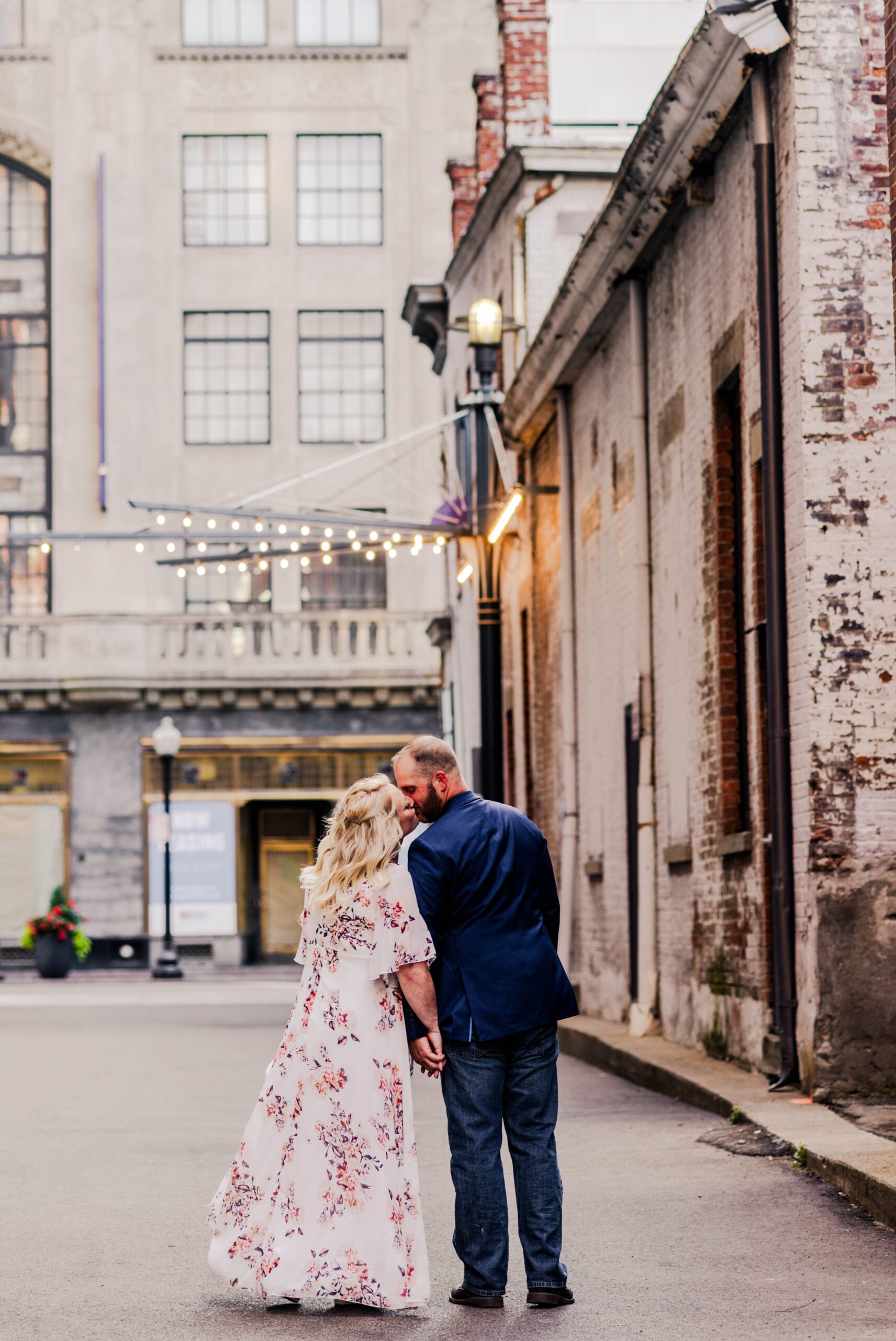 engaged couple holding hands looking at each other as they walk down an alley in downtown Cincinnati during their engagement photos