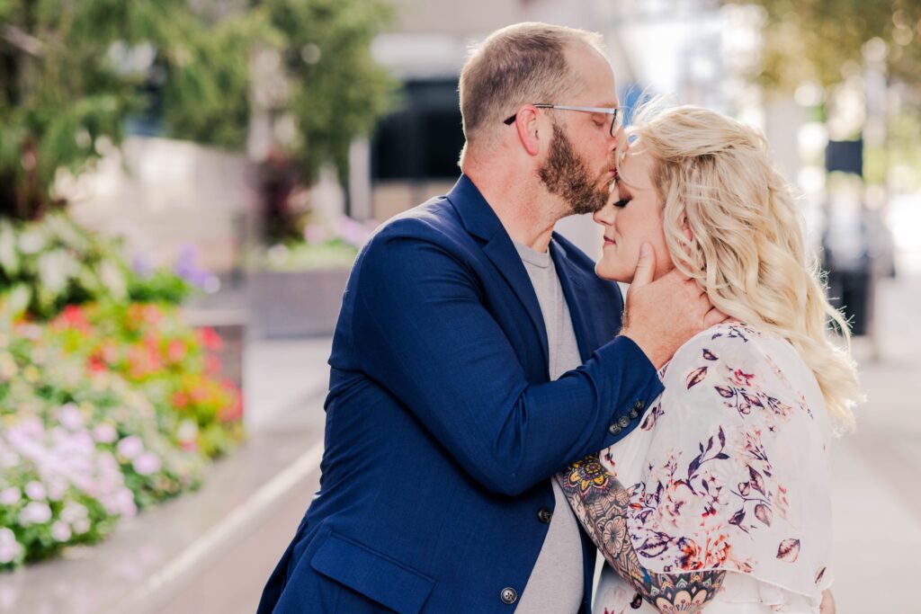 Tattooed blond woman being kissed on the forehead by her fiancé in downtown Cincinnati