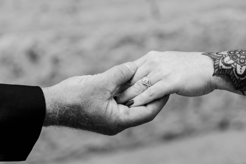 close up Black and white photos of two hands holding each other highlighting the engagement ring