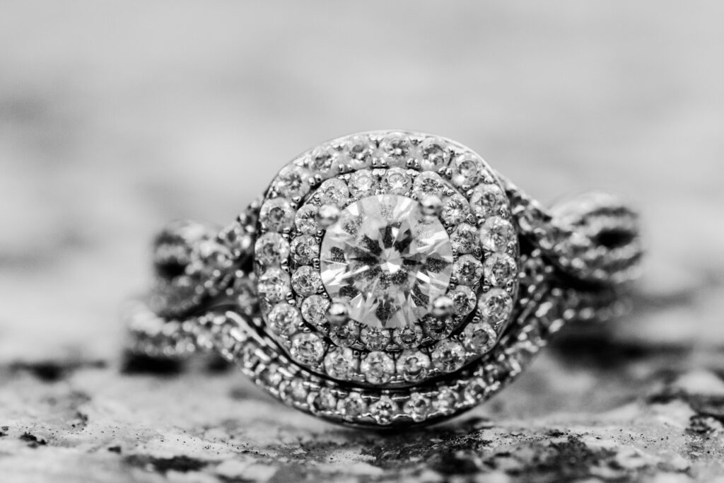 Black and white close up image of a diamond ring sitting on a stone wall