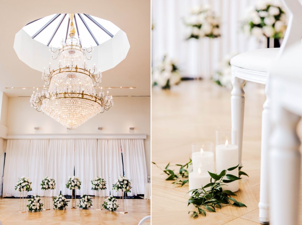 Ceremony details of a large chandelier and white florals with greenery. 