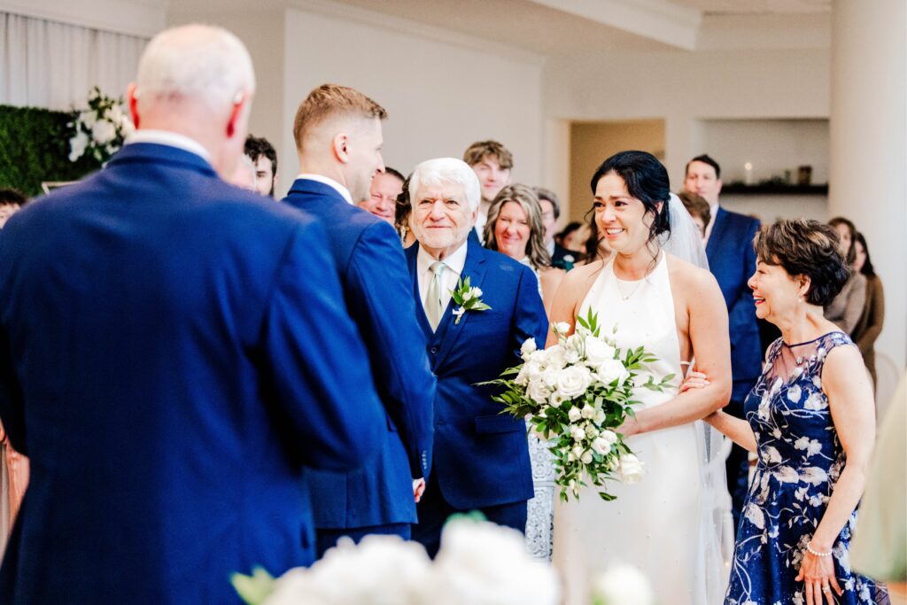 Bride at with her parents meeting the groom at the end of the aisle full of emotions