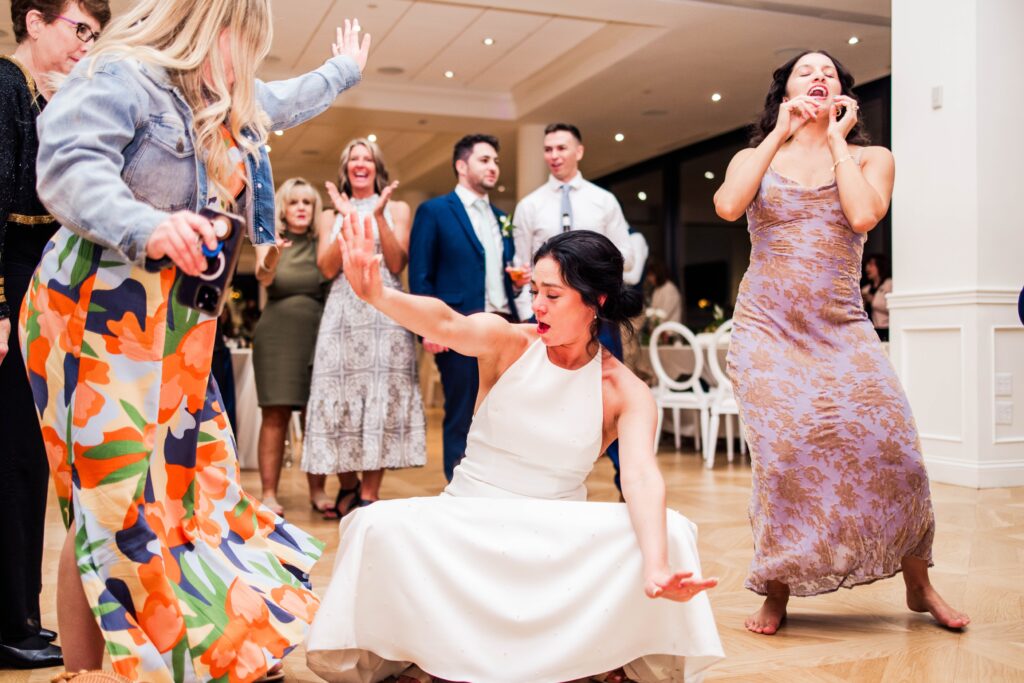 Bride dropping it low on the dance floor with her guest cheering her on