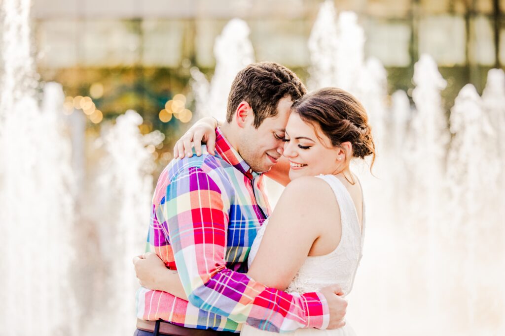 Engaged couple hugging during golden hour engagement session in front of water fountain