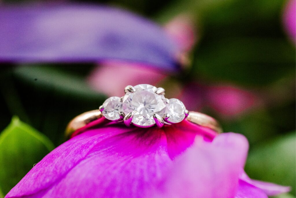 engagement ring sitting on top of purple flower